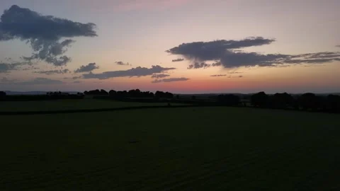 Aerial Sunset Over Green Fields and Rolling Countryside Stock Footage 332566543