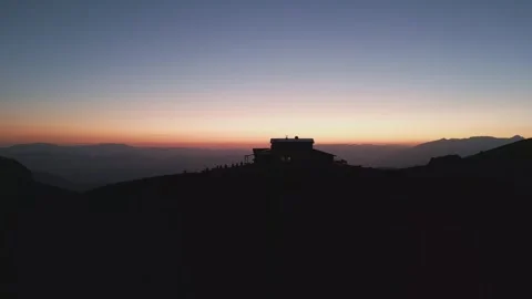 Aerial sunset over mountain refugee camp, silhouetted panorama, red-blue sky Stock Footage 320957103