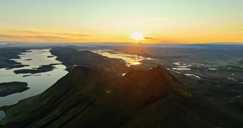 Aerial sunset over sharp mountain ridges and winding lakes, with golden Stockbeeldmateriaal 333223540