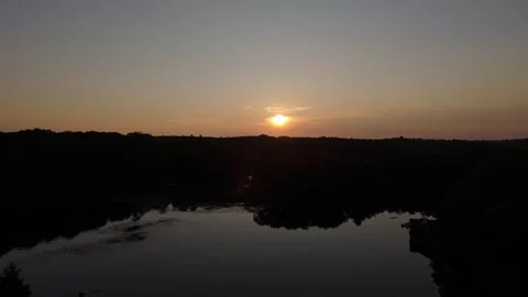 Aerial of sunset then down to hide sunset behind trees Stock Footage 251565021