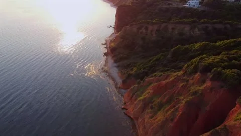 Aerial sunset view of dramatic coastal cliffs and golden sea reflection Vídeo Stock 331442972