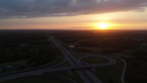 Aerial sunset view of a highway interchange cutting through forest landscape Stock Footage 324520125