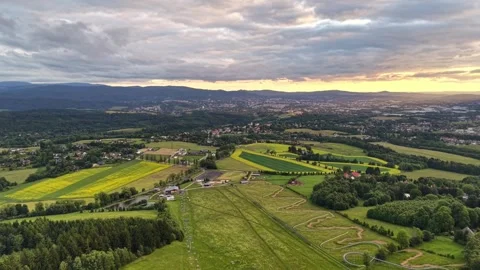 Aerial sunset view of patchwork fields, rolling hills, winding trails, and Stock Footage 347915388