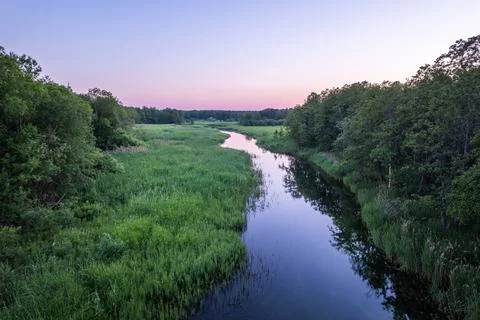 Aerial sunset view on a river with smooth mirror surface through a forest Stock Photos