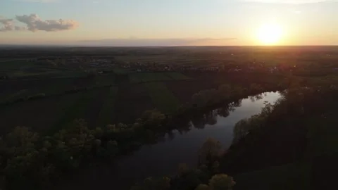 Aerial sunset view of river winding through green rural fields and forest, Stock-Footage 314407531