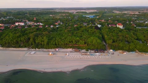 Aerial sunset view of sandy beach on the sea coast and forest with small town Stock Footage 155710992