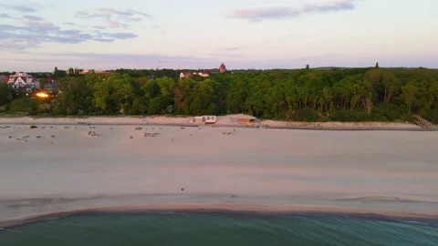 Aerial sunset view of sandy beach on the sea coast and forest with small town Video stock 155809144