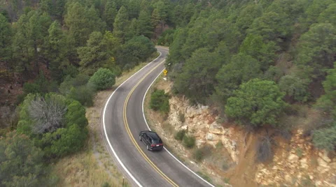 AERIAL: SUV car driving along the winding mountain pass road through the forest Stock Footage