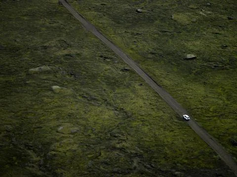 Aerial of SUV driving on gravel road through Icelandic lava field Stock Photos