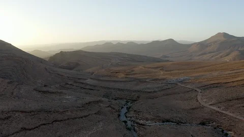 An aerial of an SUV on a thin, winding road in a barren mountain desert. Stock Footage 127016463
