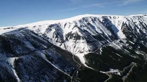 Aerial of switchback road meandering under mountain ridge covered with snow 스톡 동영상 124225977