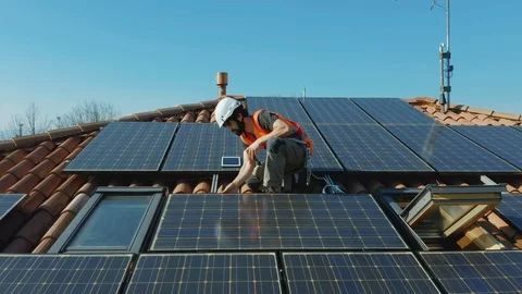 Aerial Technician with hard hat installing solar panel installed on home rooftop Stock Footage