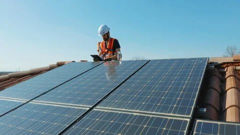 Aerial Technician with hard hat installing solar panel installed on home rooftop Stock Footage