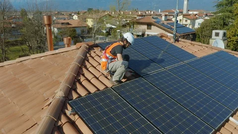 Aerial Technician with hard hat installing solar panel installed on home rooftop Stock Footage 127669902