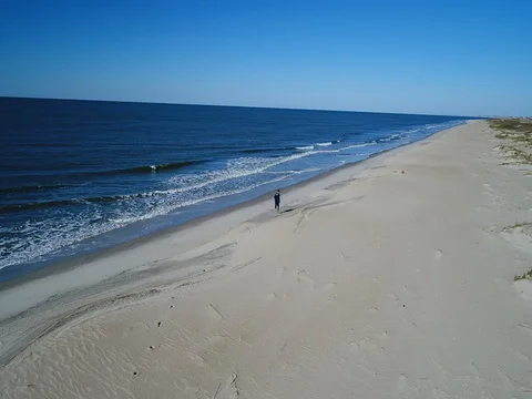 Aerial of a teenage boy running along the beach Stock Footage