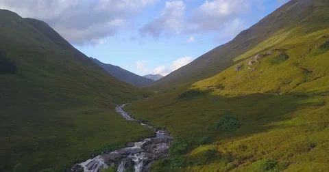Aerial of thin stream of water flowing between the lush green mountains Video stock 81534161