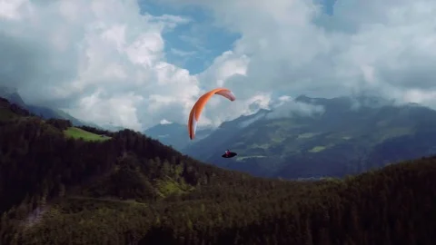 Aerial of three men paragliding over the green hills and valley on a sunny day Stock Footage 76141153