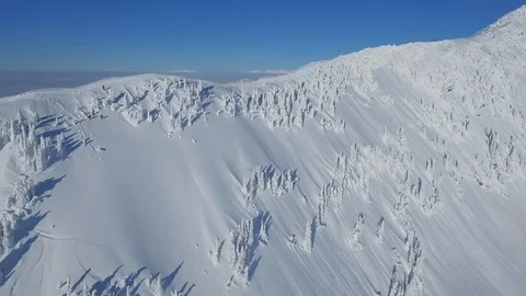 Aerial of three snowboarders sliding down snowy hill on sunny day, Canada Stock Footage 124222583