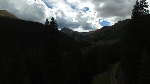 Aerial Through Trees Toward Mountain Range With Valley River In Foreground Stock-Footage 102141491
