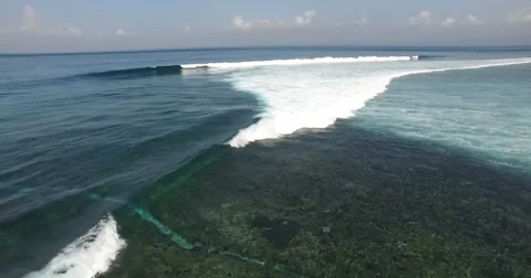 AERIAL tilt down and right following waves breaking towards beach Stock Footage 59886664