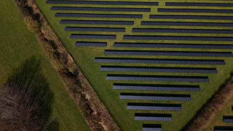 Aerial tilt-up large solar panel farm beside highway in USA, showing rows of Vídeo Stock 332820295