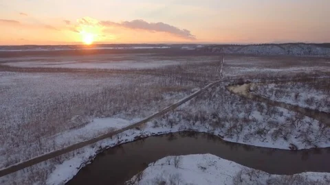 Aerial tilt up on snowy landscape with river at sunset Video stock 73011953