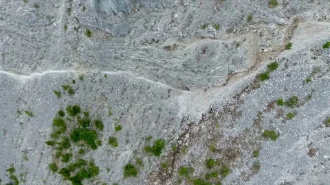 Aerial: tilted down while moving over edge of vertical mountain cliff Stock Footage 72403567