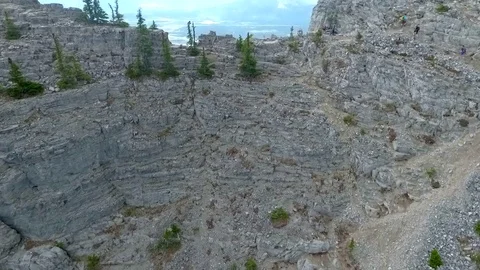 Aerial: tilting down while moving over edge of vertical mountain cliff Video stock 72395525