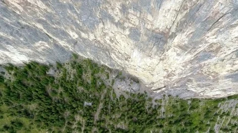 Aerial: tilting down while moving over edge of vertical mountain cliff Video stock 72420943