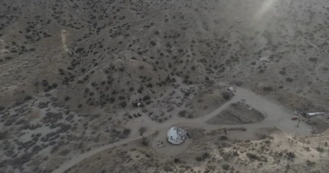 Aerial tilts down over a geodesic dome structure in the California desert Vidéo 150769442