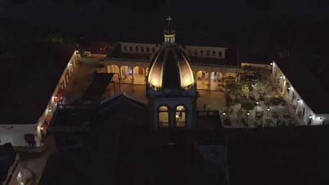 Aerial tilts down over the top of Maria Imaculada church in Mompox at night Stock Footage 108543506