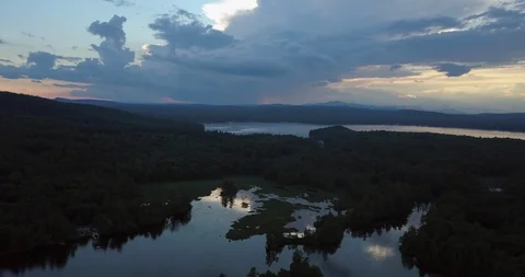 Aerial timelapse as clouds flow over sunset reflective lake Video stock 111523585