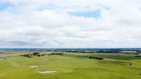 Aerial timelapse of clouds moving across an open field of green grass Stock Footage 156413630