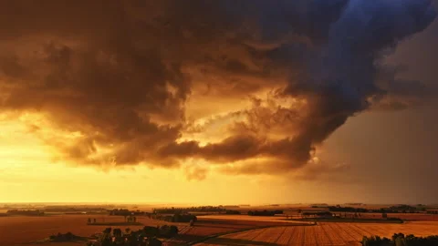 Aerial timelapse of dramatic storm clouds sweeping across farmland at sunset Stock Footage 323805928