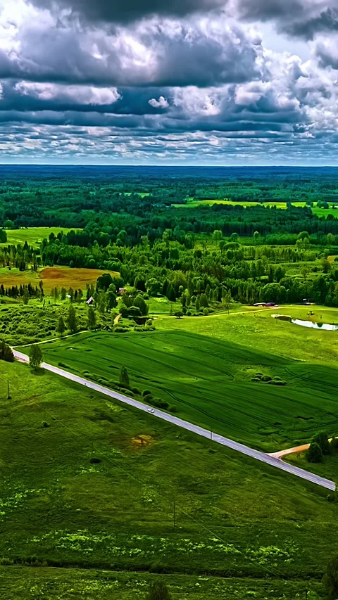 Aerial Timelapse of Lush Green Fields and Road Under Dramatic Cloudy Sky Stock Footage 340565814