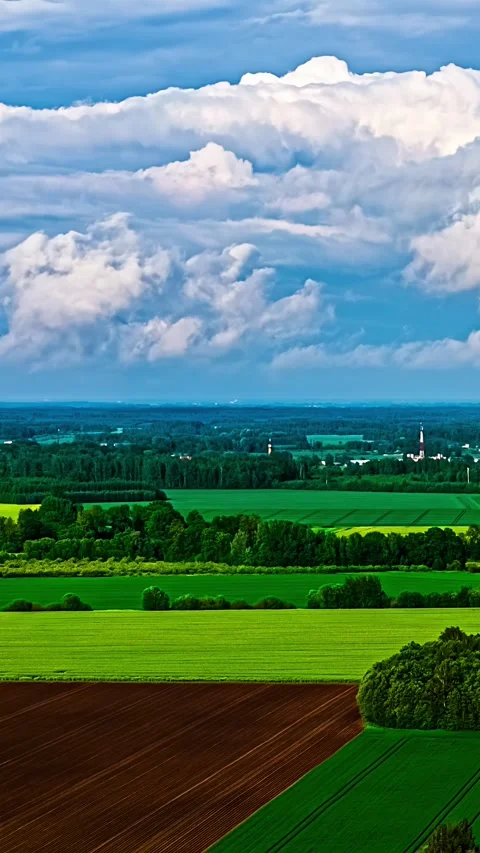 Aerial timelapse of massive white cumulus clouds over green fields and Stock Footage 345131434
