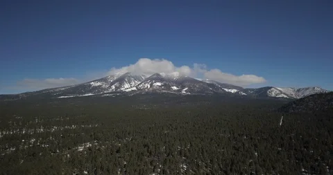 Aerial timelapse of wispy clouds rolling over mountain peaks above a pine forest Stock Footage 101858313