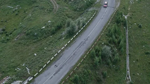 Aerial top-down 4K view of a red car driving on a country road in the woods Stock Footage 124863279