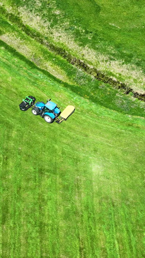 Aerial Top Down Of Blue Tractor Mowing Green Grass Field Video stock 336566975