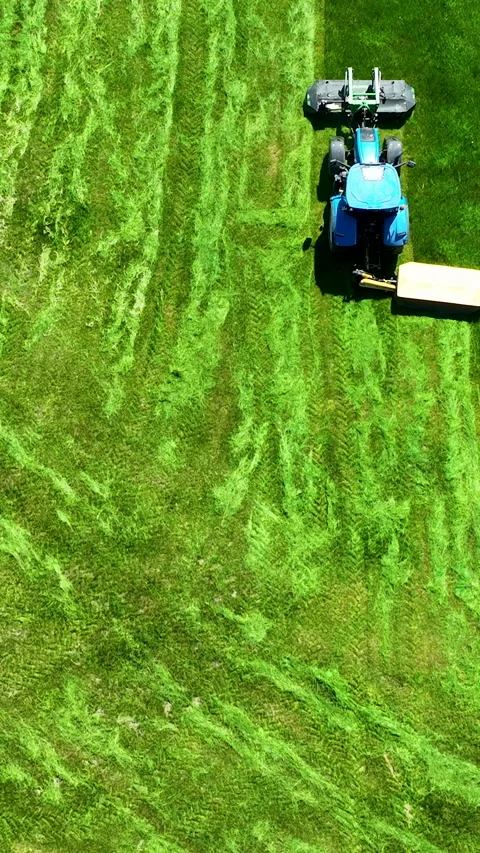 Aerial Top Down Of Blue Tractor Mowing Green Grass Field Video stock 336567118