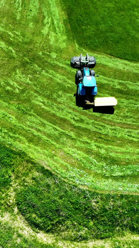 Aerial Top Down Of Blue Tractor Mowing Green Grass Field In Lidzbark Video stock 336567467