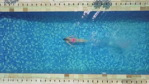 AERIAL TOP DOWN CLOSEUP Unrecognizable woman enjoys swimming underwater in pool Stock Footage