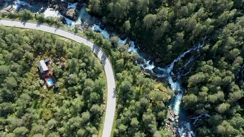 AERIAL, TOP DOWN: Dark colored car driving down an asphalt road crossing the  Vidéo 115559295
