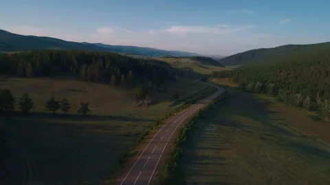 AERIAL, TOP DOWN: Dark colored car driving down an asphalt road crossing the Stock Footage 125466385