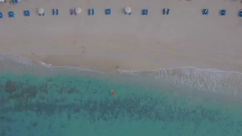 Aerial top down drone shot of sea kayaker paddling out from beach Stock Footage 137497940