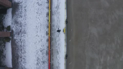 Aerial top down drone shot of person walking along snowy sidewalk Stock Footage 146295024