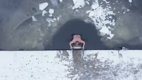 Aerial top down drone shot of man getting out of a frozen lake Stock Footage 146295142