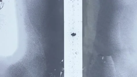 Aerial top down drone shot of person walking along snowy boardwalk Stock Footage 146295255