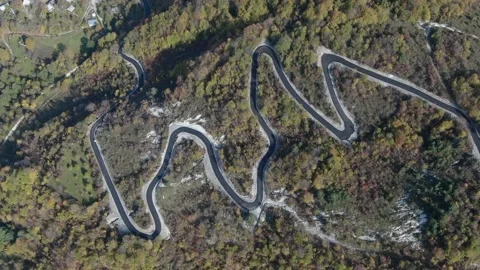 Aerial top down drone shot above the Autumn mountain road between the trees Video stock 237810293