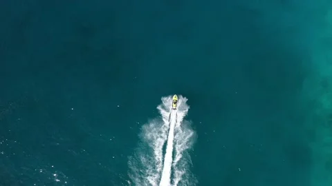 Aerial Top Down Drone shot of a jet ski racing on blue ocean water. Stock Footage 239822774